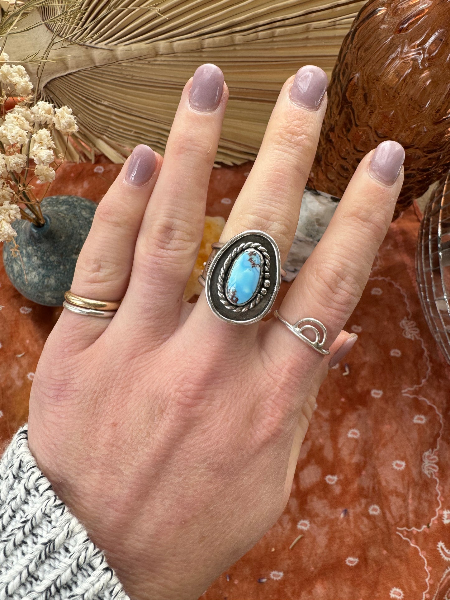 a female hand showing a turquoise ring on her middle finger